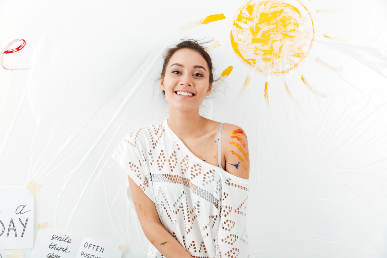 Smiling young woman in white shirt with sun painted behind her