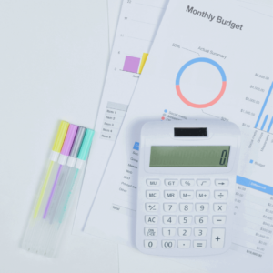 Image of a calculator and pages of charts with colorful pens to make notes.