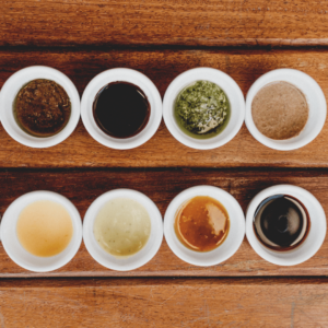 Image of eight unlabeled sauces on a wooden table.